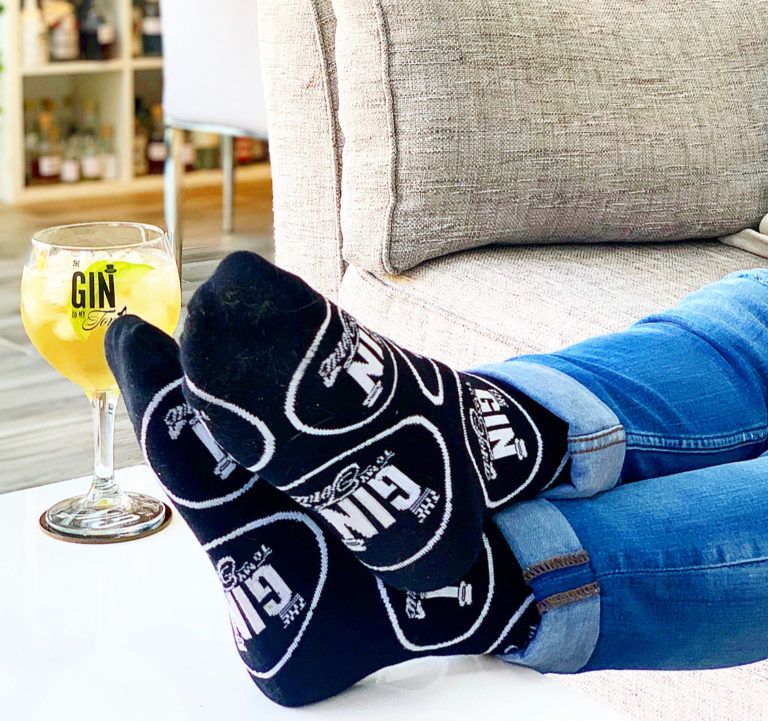 The Gin To My Tonic Socks worn on feet resting on the table with gin copa glass in the background