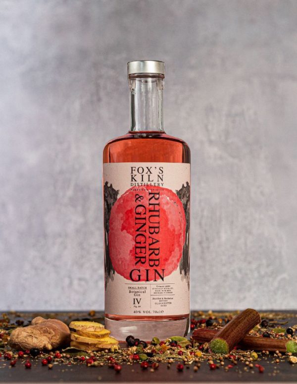 Rhubarb & Ginger Gin 70cl bottle surrounded with botanicals on grey background